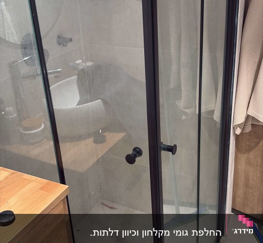 מקלחון זכוכית עם מדף מוצרים בחדר אמבטיה